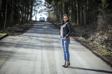 The girl in jeans and a black jacket standing on the road