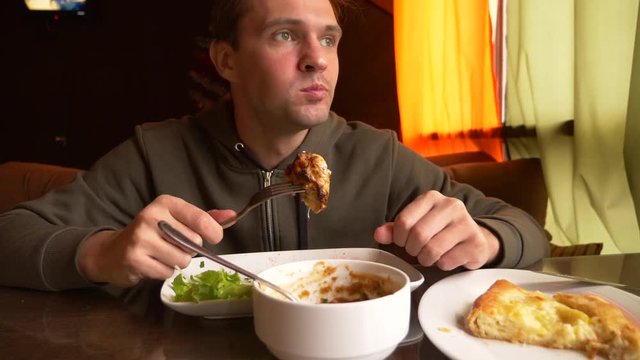 the man in the restaurant eats hot meat with a fork, 4k, slow-motion shooting