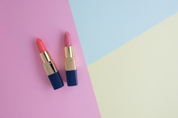 Flat lay minimal concept of creative female cosmetic for pink and orange lipstick on the colorful background with copy space