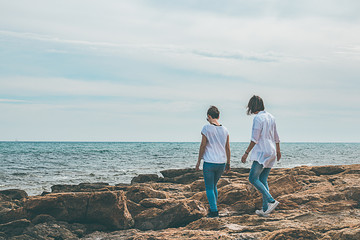 Two girls walking by the sea