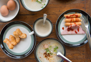 Flay lay of breakfast with sausage, ham, egg, coffee, mush and deep-fried dough stick