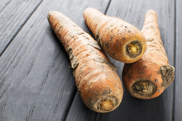 natural carrot with slices of dirt, on a black board