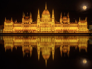 Fototapeta premium Hungarian Parliament Building (Budapest) at night reflected in water of Danube River and with full Moon above it