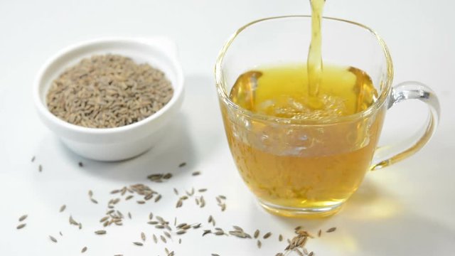 Pouring cumin tea in a cup. Cumin tea prepared by heating cumin seeds and water, also called as Jeera tea or Jeera water.