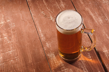 Fresh and cold beer in glass. Tasty beer concept on wooden background.