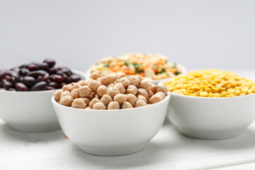 Different beans in bowls on a white wooden table