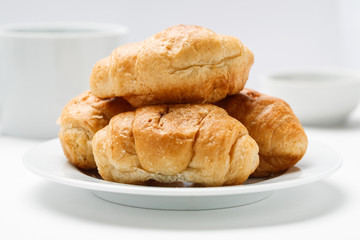 Fresh croissant in a white plate on a white table, closeup