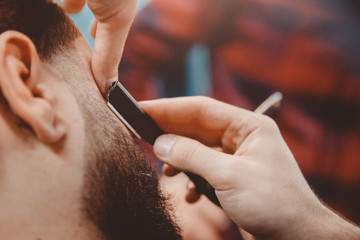 Man with beard client in barbershop hairdresser on shaving with dangerous razor.