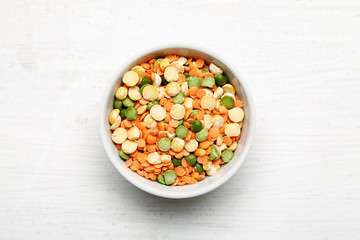 Different beans in bowls on a white wooden table, top view
