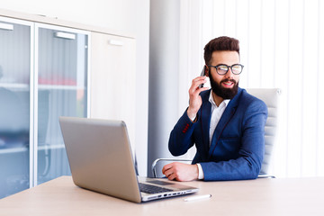 Young Businessman Talking On Phone While Works On Laptop