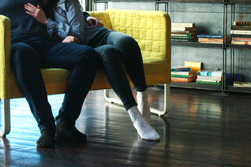 A couple is sitting on the sofa near the bookshelf.