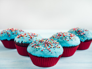 Festive, fragrant cupcakes, covered with turquoise glaze and bright decoration for baking on a white background