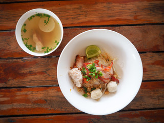 Closeup of hot noodles. Thai local noodle. Thai style pork spicy noodle soup. Pork noodle spicy soup ,Thai noodle,Tom yum. Bowl With spoon and chopsticks on wooden table.