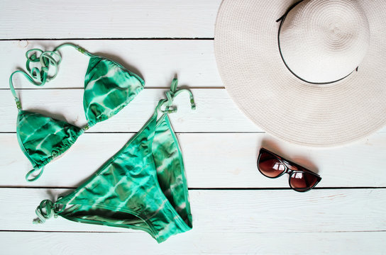 Green bikini suit, hat, sunglasses, sea star arranged on wooden baclground. Summer holidays vacation concept. Tropical poster banner, postcard.