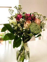 Close-up of beautiful bridal bouquet sitting in a vintage jar on a white table and aery atmosphere
