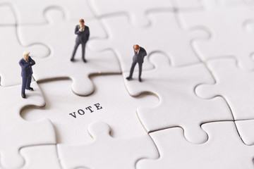 Miniature men on jigsaw puzzle with word vote