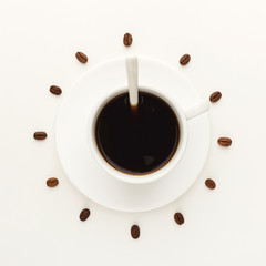 Black coffee cup and roasted beans forming clock dial isolated on white