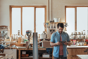Young carpenter using a digital tablet in his workshop