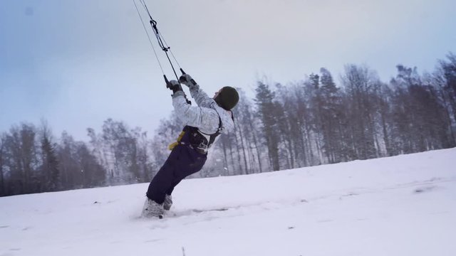 A male athlete in sports outfit is doing snow kiting on beautiful winter landscape