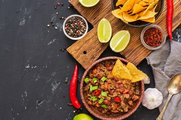 Chili con carne with nachos chips on rustic background.Mexican food. Place for text, top view.