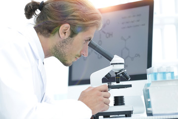 senior lab technician using microscope in laboratory