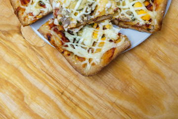 Plate with slices of homemade pizza with mushrooms and ham on wooden background