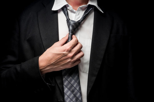 Close up of businessman taking off his tie on black background
