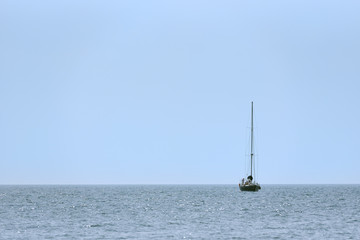 A small sailing ship with sails down, one at sea