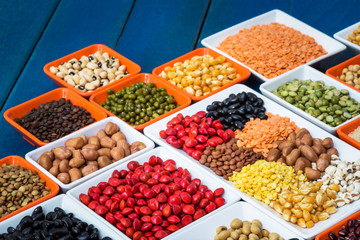 Different dry legumes in container on blue plank, Prepared multicolor dried beans ontable for cooking
