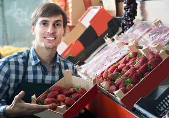 Grocery worker selling fresh strawberry at local market