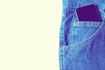 Black modern smartphone in the pocket of old vintage indigo stonewashed jeans. Concept of daily...