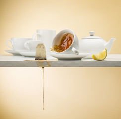falling cup of tea on white table with tea bag dripping and lemon slice