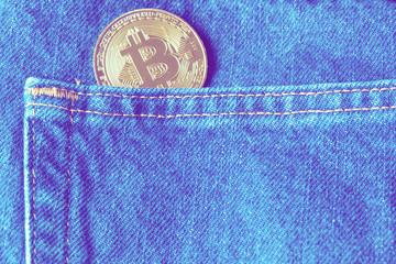 Golden bitcoins in the pocket of old vintage indigo stonewashed jeans. Concept of bitcoin - a...