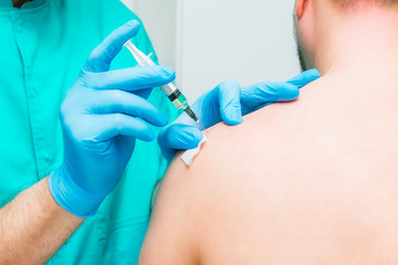 Close up Neurologist doctor makes an injection therapy, blockade into deltoid muscle of male patient. Alternative pain treatment concept. Selective focus, space for text.