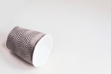 Lying disposable cup on a light  paper background. Candid, copy space.