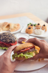 Eating burger. Delicious hamburger in the male hands. Fastfood unhealthy meal.