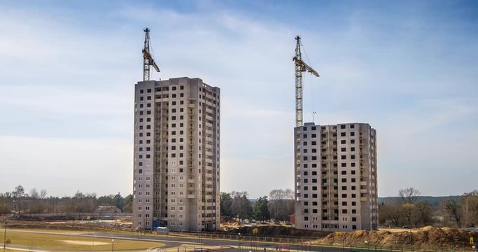 Time lapse of silhouettes of cranes working on a construction site of a multi-storey building in sunny spring day