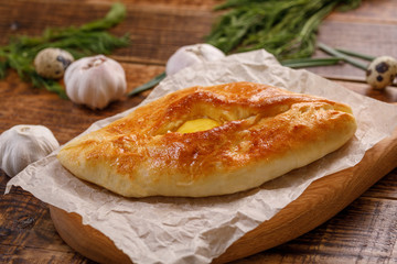 Traditional grzina baking. Khachapuri with egg close-up on a wooden background.