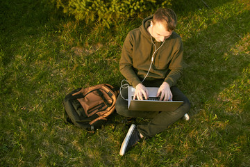 young man working in laptop sitting on grass
