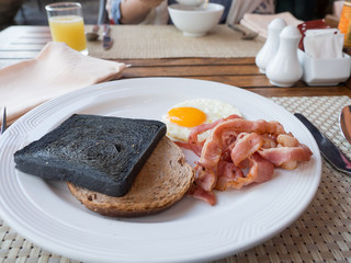 Breakfast with nutritious have Bread Charcoal,toast,bacon and egg on a white plate.orange juice,Salt and pepper on the background.