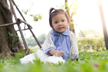 Cute little girl is playing with leaf on grass field at green park, Ecology friendly , healthy and lifestyle concept