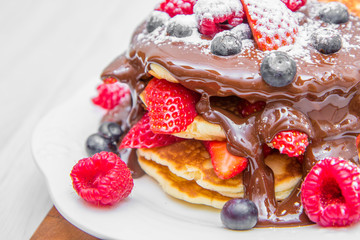 dish with pancakes and strawberry,raspberry and blueberry and chocolate 