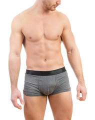 Muscular young man wearing boxer briefs isolated on white background.