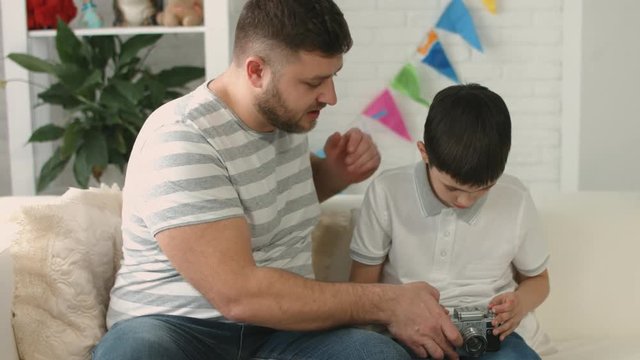 Dad presents camera to his son and teaches him how to work with it