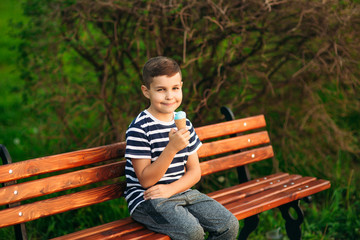 A little boy in a striped T-shirt is eating blue ice cream.Spring, sunny weather