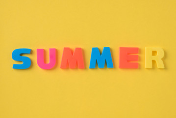 The summer inscription with plastic letters on a yellow background