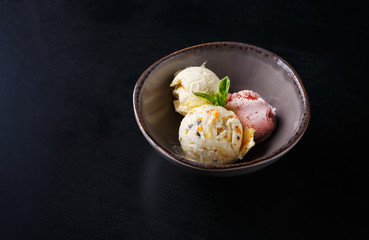 Assorted ice cream scoops in bowl on black