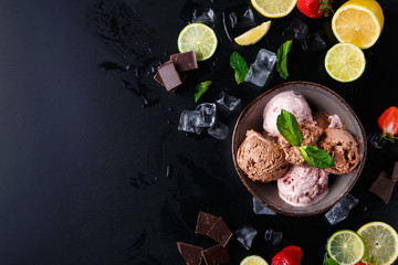 Portion of ice cream scoops with fruit on black