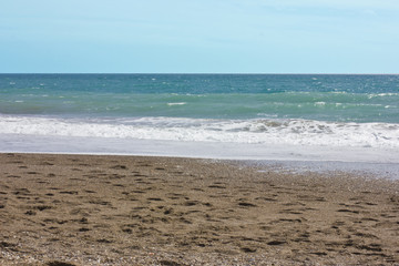 Summer sea and blue sky, white sea foam on a yellow sandy beach.