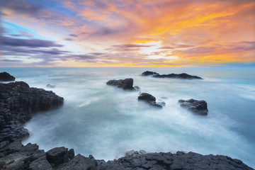 Obraz premium Beautiful Sunset at Menganti beach of Indonesia, Sunset and rocks on the beach